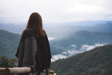 Sisli bir günde tek başına oturmuş dağları seyreden bir kadın.