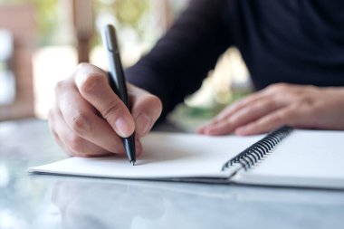 Masaya boş not defterine yazı yazan ellerin yakın plan resmi 