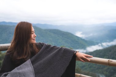 Sisli bir günde tek başına oturmuş dağları seyreden bir kadın.