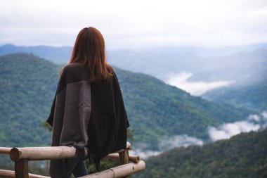 Sisli bir günde tek başına oturmuş dağları seyreden bir kadın.