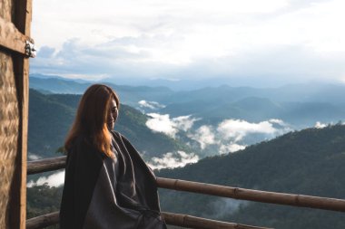 Sisli bir günde tek başına oturmuş dağları seyreden bir kadın.