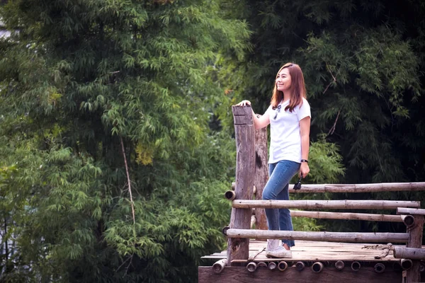 緑豊かな自然の背景を持つ家の前に木製のバルコニーに立つ美しいアジアの女性 — ストック写真