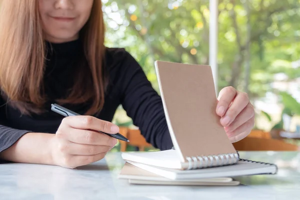 緑の自然を背景にテーブルの上に書き込むために空白のノートを保持し 開いているビジネス女性のクローズアップイメージ — ストック写真