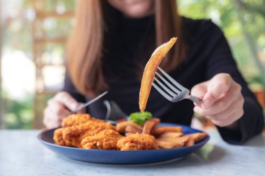 Restoranda patates kızartması ve kızarmış tavuk yemek için çatal ve bıçak kullanan bir kadının yakın plan görüntüsü.