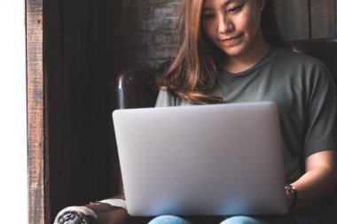 Kanepede otururken bilgisayarında çalışan ve daktilo kullanan bir kadının yakın plan görüntüsü.