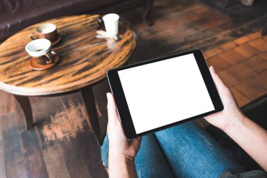 Kafede otururken siyah tableti beyaz masaüstü ekran ile tutan kadınların ellerinin görüntüsü