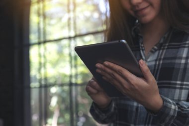 Gülücük yüzlü, güzel bir Asyalı kadın modern kafede tablet tablet kullanıyor.