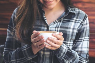 Kafede iyi hissederek içmeden önce elinde kahve fincanı tutan Asyalı bir kadının yakın plan görüntüsü.
