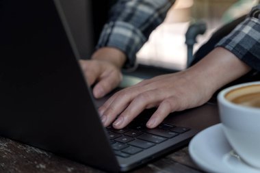 Laptop klavyesinde çalışan ve daktilo kullanan bir kadının yakın plan fotoğrafı.