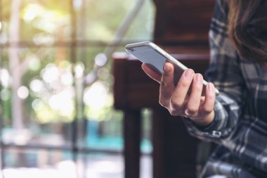 Elinde tutan, kullanan ve akıllı telefona bakan bir kadının yakın plan görüntüsü. 