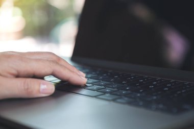 Laptop klavyesinde çalışan ve yazı yazan bulanık arkaplanlı ellerin yakın plan resmi