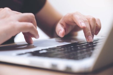 Laptop klavyesinde çalışan ve yazı yazan bulanık arkaplanlı ellerin yakın plan resmi