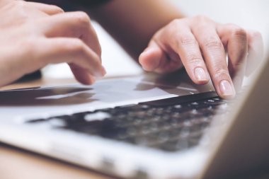 Laptop klavyesinde çalışan ve yazı yazan bulanık arkaplanlı ellerin yakın plan resmi