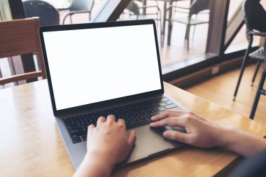 Kafe 'deki boş beyaz masaüstü ekranı ile laptopta yazı yazan ve kullanan bir elin görüntüsü