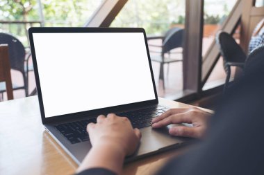 Kafedeki boş beyaz ekranla iş kadınının laptopta yazma ve kullanma görüntüsü