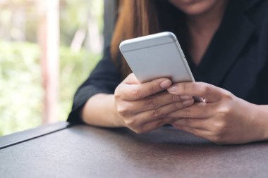 Elinde tutan, kullanan ve akıllı telefona bakan bir kadının yakın plan görüntüsü.