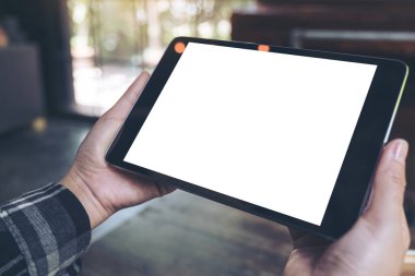 Kafede boş beyaz masaüstü ekranı olan siyah tableti tutan ellerin görüntüsü