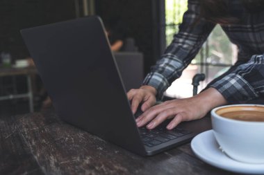 Laptop klavyesinde çalışan ve daktilo kullanan bir kadının yakın plan fotoğrafı.