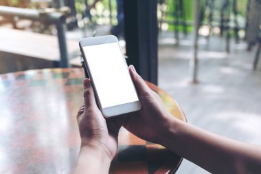Boş masaüstü ekranı ve ağaç kabı olan beyaz cep telefonunu tutan ellerin görüntüsü 