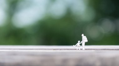 Baba ve kızının arka planı bulanık, ahşap masada birlikte yürüdüğü minyatür figürün yakın çekimi.