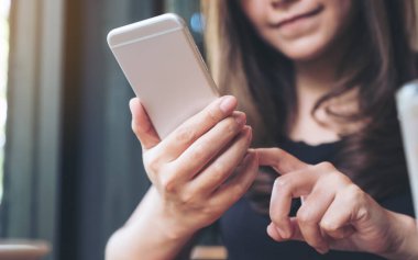 Elinde tutan, kullanan ve akıllı telefona bakan bir kadının yakın plan görüntüsü. 