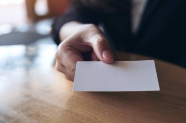 İş kadını ofisteki masadaki birine boş bir kartvizit veriyor.