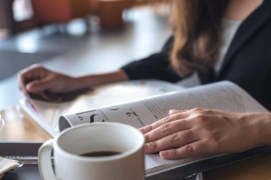 Kafe 'de kahve fincanı ile kitap okuyan bir iş kadınının yakın çekimi. 