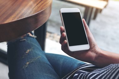 Beyaz cep telefonunu boş ekran ile tutan kadınların ellerinin görüntüsü. 