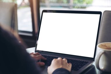 Kafe 'deki boş beyaz ekranla iş kadınının laptopta yazı yazıp kullandığı bir resim.