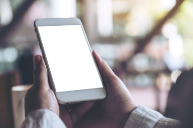 Kafede boş masaüstü ekranı olan beyaz cep telefonu tutan ellerin görüntüsü