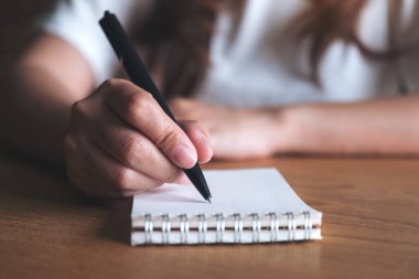 Masaya beyaz boş bir defter yazan bir kadının yakın plan resmi. 