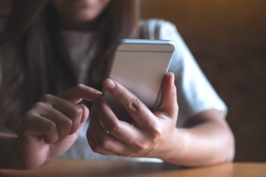 Kafedeki boş masaüstü ekran ile beyaz cep telefonu tutan kadınların görüntüsü