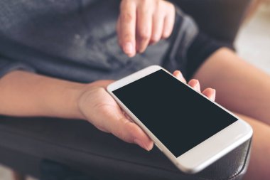 Siyah ekranlı beyaz bir cep telefonunu tutan ve işaret eden bir kadının görüntüsü. 