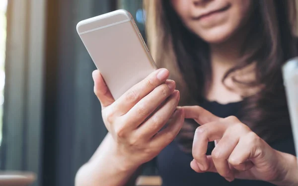 Elinde tutan, kullanan ve akıllı telefona bakan bir kadının yakın plan görüntüsü. 