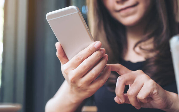 Крупный план женщины, держащей, использующей и смотрящей на смартфон 