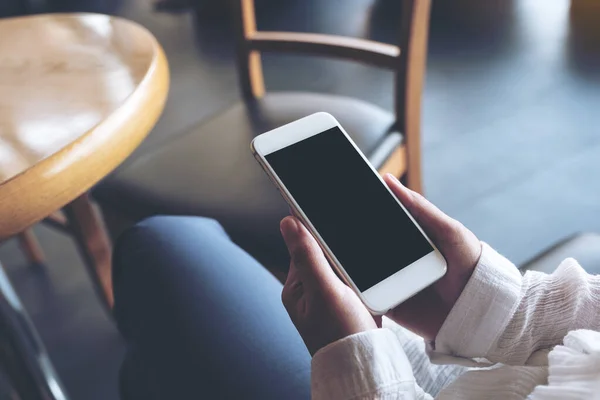 stock image Mockup image of hands holding white mobile phone with blank black desktop screen 