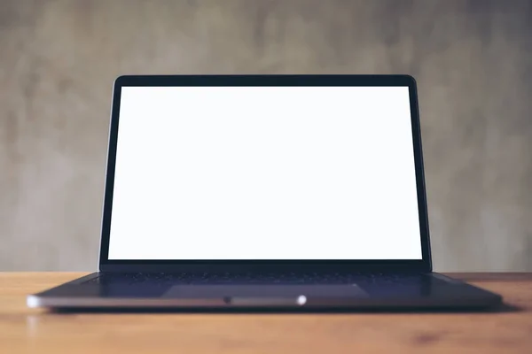 コンクリート壁の背景と木製のテーブルの上に空白の白いデスクトップ画面とラップトップのモックアップイメージ — ストック写真