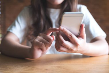 Kafedeki boş masaüstü ekran ile beyaz cep telefonu tutan kadınların görüntüsü