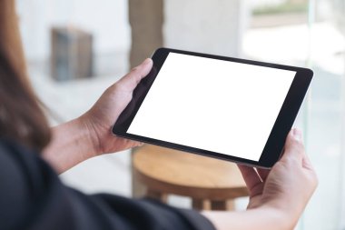 Kafe 'de elinde boş beyaz masaüstü ekranı olan siyah tablet bir kadının görüntüsü