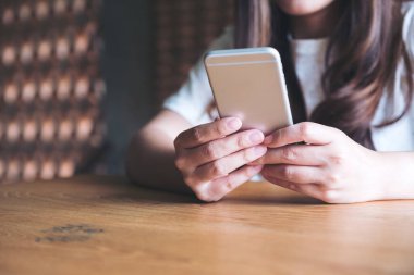 Kafedeki boş masaüstü ekran ile beyaz cep telefonu tutan kadınların görüntüsü