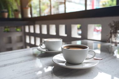 Kafedeki masada iki fincan sıcak kahvenin yakın plan görüntüsü.