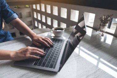 Laptop klavyesinde çalışan ve daktilo kullanan bir kadının yakın plan fotoğrafı.