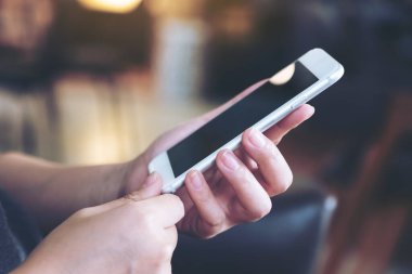 Kafede bir kadının elini tutarken ve akıllı telefon kullanırken yakın plan görüntüsü.