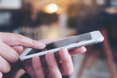 Kafede bir kadının elini tutarken ve akıllı telefon kullanırken yakın plan görüntüsü.