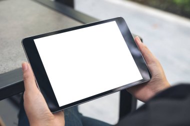Boş beyaz masaüstü ekranlı siyah tableti tutan ellerin görüntüsü 
