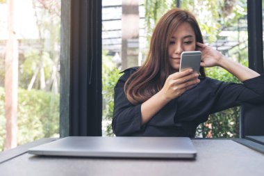 Kafedeki boş masaüstü ekran ile beyaz cep telefonu tutan kadınların görüntüsü