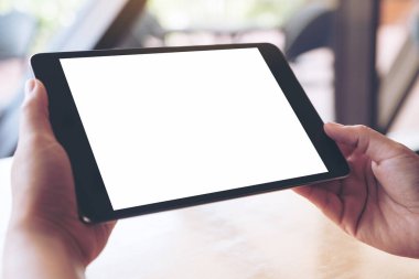 Elleri tutan ve boş beyaz masaüstü ekranlı siyah bir tablet pc kullanan elleri görüntüle 