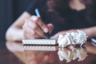 Bir iş kadınının çalışma ve yazı yazma görüntüsü beyaz boş bir defter ve masa üzerinde berbat kağıtlar.