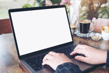 Kafe 'deki boş beyaz masaüstü ekranı ile laptopta yazı yazan ve kullanan ellerin görüntüsü