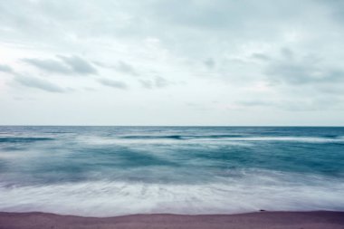 Mavi gökyüzü arka planlı tropikal beyaz sahilde dalgalar